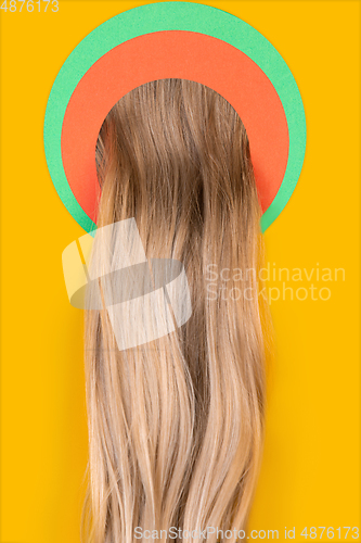 Image of Female long hair peeking throught circle in yellow background