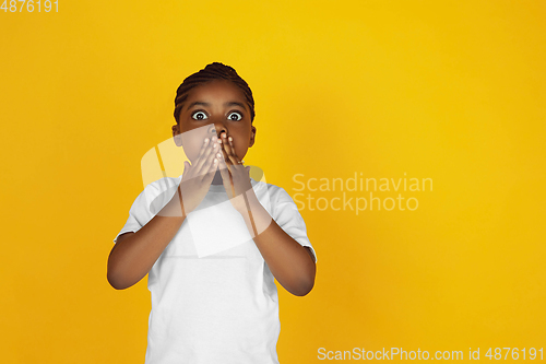 Image of Little african-american girl\'s portrait isolated on yellow studio background