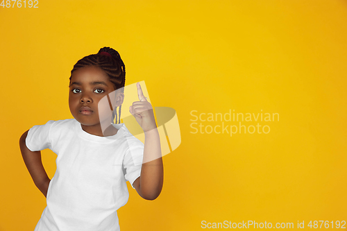 Image of Little african-american girl\'s portrait isolated on yellow studio background