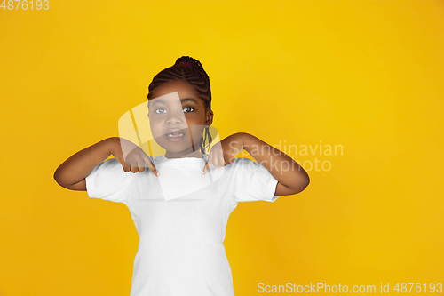 Image of Little african-american girl\'s portrait isolated on yellow studio background