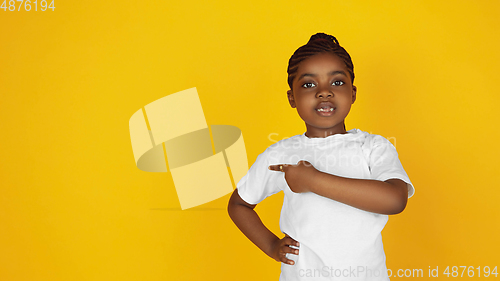 Image of Little african-american girl\'s portrait isolated on yellow studio background