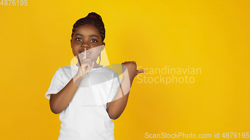 Image of Little african-american girl\'s portrait isolated on yellow studio background