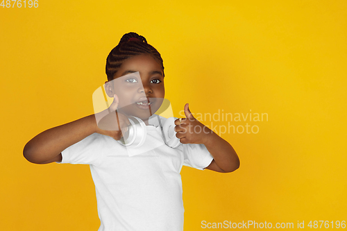 Image of Little african-american girl\'s portrait isolated on yellow studio background