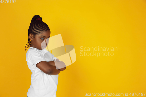 Image of Little african-american girl\'s portrait isolated on yellow studio background