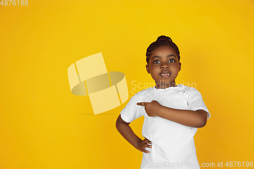 Image of Little african-american girl\'s portrait isolated on yellow studio background