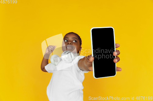 Image of Little african-american girl\'s portrait isolated on yellow studio background