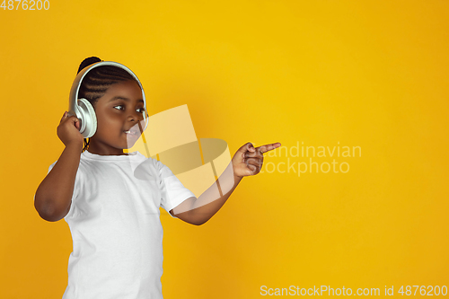 Image of Little african-american girl\'s portrait isolated on yellow studio background