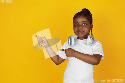 Image of Little african-american girl\'s portrait isolated on yellow studio background