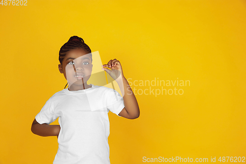 Image of Little african-american girl\'s portrait isolated on yellow studio background