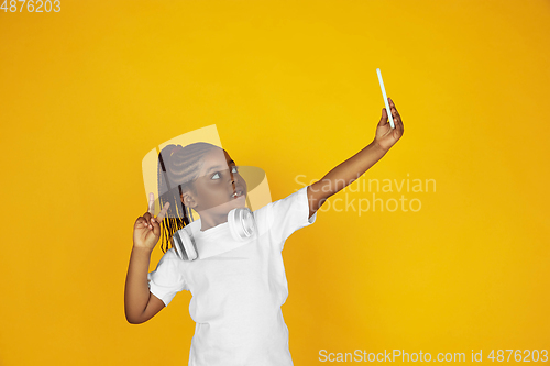 Image of Little african-american girl\'s portrait isolated on yellow studio background