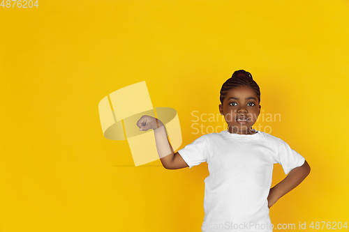 Image of Little african-american girl\'s portrait isolated on yellow studio background