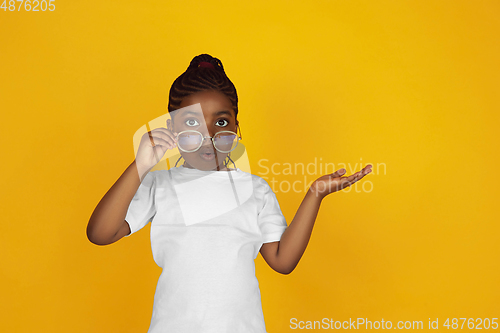 Image of Little african-american girl\'s portrait isolated on yellow studio background