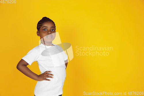 Image of Little african-american girl\'s portrait isolated on yellow studio background
