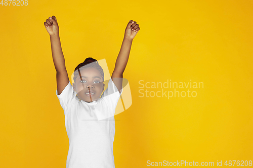 Image of Little african-american girl\'s portrait isolated on yellow studio background