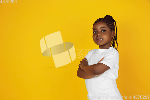 Image of Little african-american girl\'s portrait isolated on yellow studio background