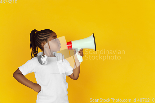 Image of Little african-american girl\'s portrait isolated on yellow studio background