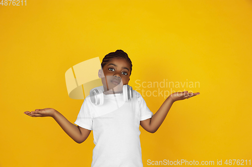 Image of Little african-american girl\'s portrait isolated on yellow studio background