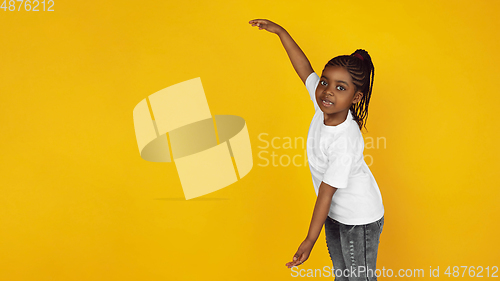 Image of Little african-american girl\'s portrait isolated on yellow studio background