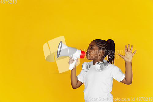 Image of Little african-american girl\'s portrait isolated on yellow studio background