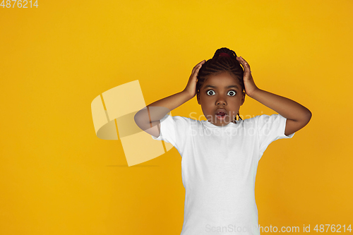Image of Little african-american girl\'s portrait isolated on yellow studio background