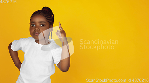 Image of Little african-american girl\'s portrait isolated on yellow studio background
