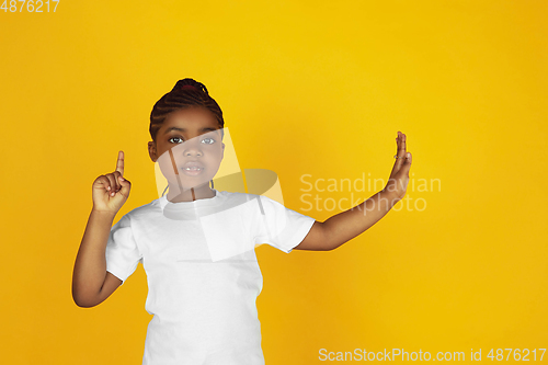 Image of Little african-american girl\'s portrait isolated on yellow studio background