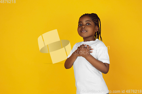 Image of Little african-american girl\'s portrait isolated on yellow studio background