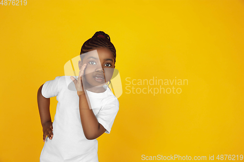 Image of Little african-american girl\'s portrait isolated on yellow studio background