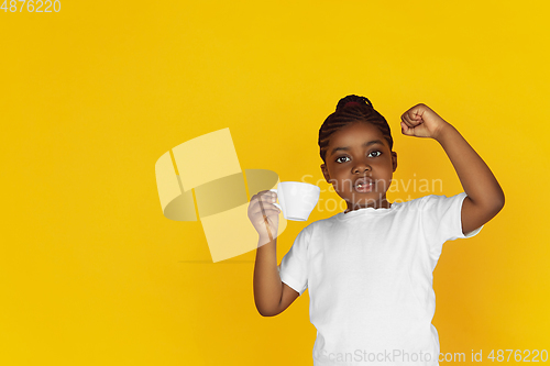 Image of Little african-american girl\'s portrait isolated on yellow studio background
