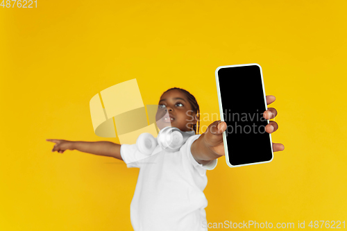 Image of Little african-american girl\'s portrait isolated on yellow studio background