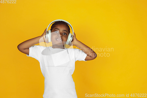 Image of Little african-american girl\'s portrait isolated on yellow studio background