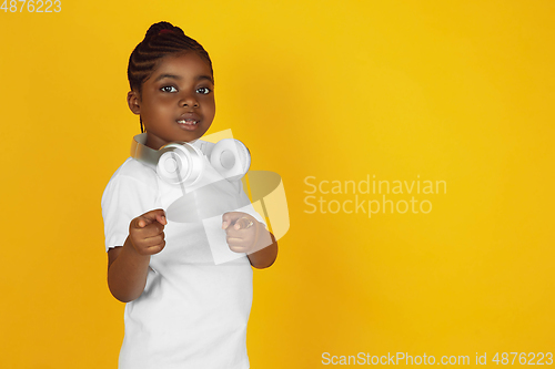 Image of Little african-american girl\'s portrait isolated on yellow studio background