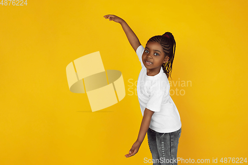 Image of Little african-american girl\'s portrait isolated on yellow studio background