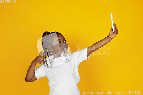 Image of Little african-american girl\'s portrait isolated on yellow studio background