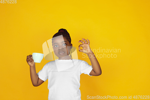 Image of Little african-american girl\'s portrait isolated on yellow studio background