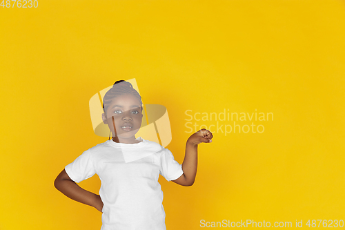 Image of Little african-american girl\'s portrait isolated on yellow studio background