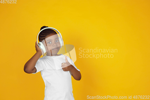 Image of Little african-american girl\'s portrait isolated on yellow studio background