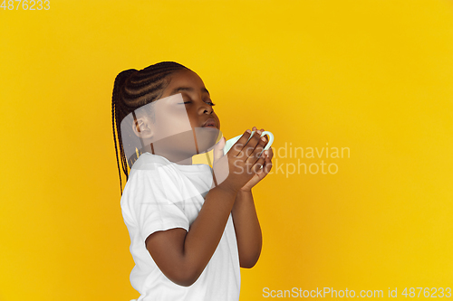Image of Little african-american girl\'s portrait isolated on yellow studio background