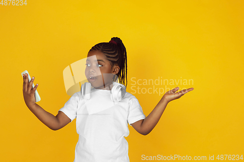 Image of Little african-american girl\'s portrait isolated on yellow studio background