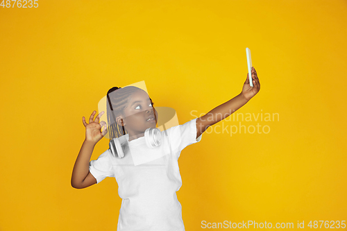 Image of Little african-american girl\'s portrait isolated on yellow studio background