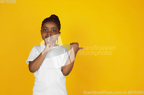 Image of Little african-american girl\'s portrait isolated on yellow studio background