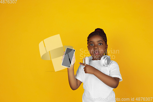 Image of Little african-american girl\'s portrait isolated on yellow studio background