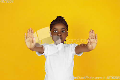 Image of Little african-american girl\'s portrait isolated on yellow studio background