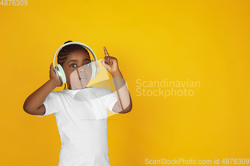 Image of Little african-american girl\'s portrait isolated on yellow studio background