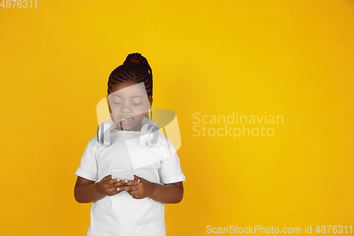 Image of Little african-american girl\'s portrait isolated on yellow studio background