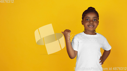 Image of Little african-american girl\'s portrait isolated on yellow studio background