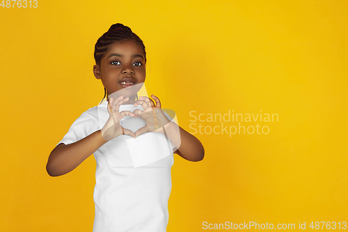 Image of Little african-american girl\'s portrait isolated on yellow studio background