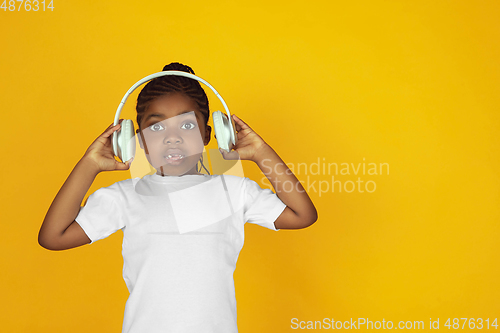 Image of Little african-american girl\'s portrait isolated on yellow studio background