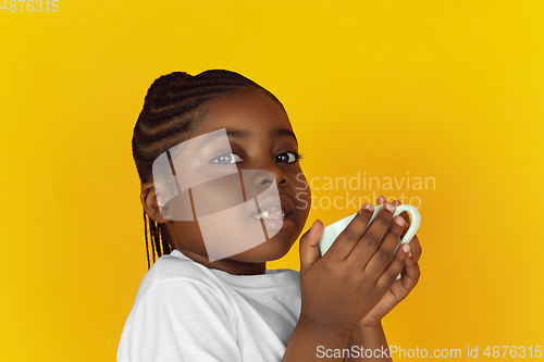 Image of Little african-american girl\'s portrait isolated on yellow studio background