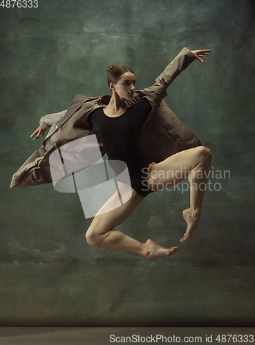 Image of Young graceful tender ballerina on dark studio background